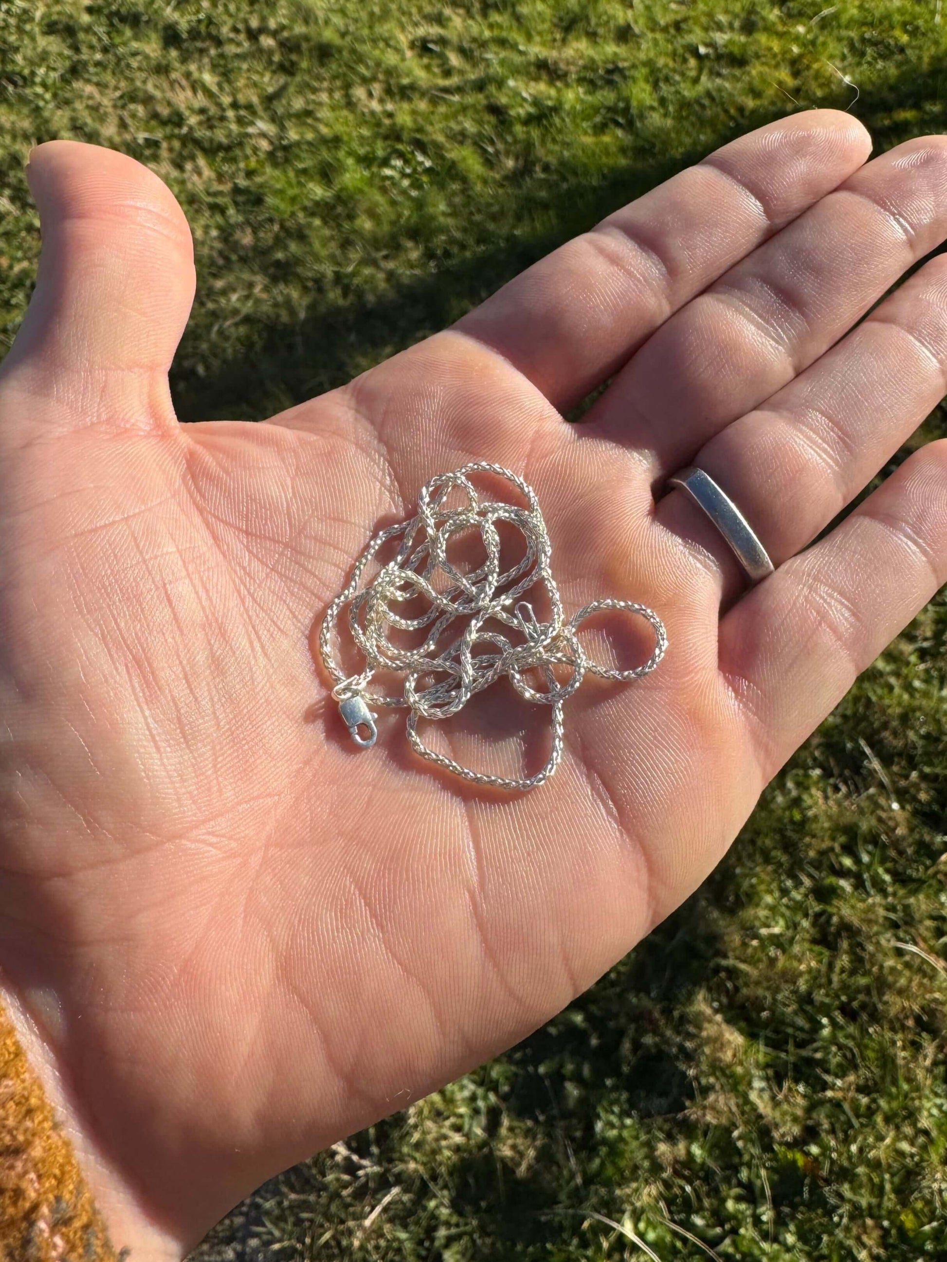 Hand holding a polished coiled silver chain 