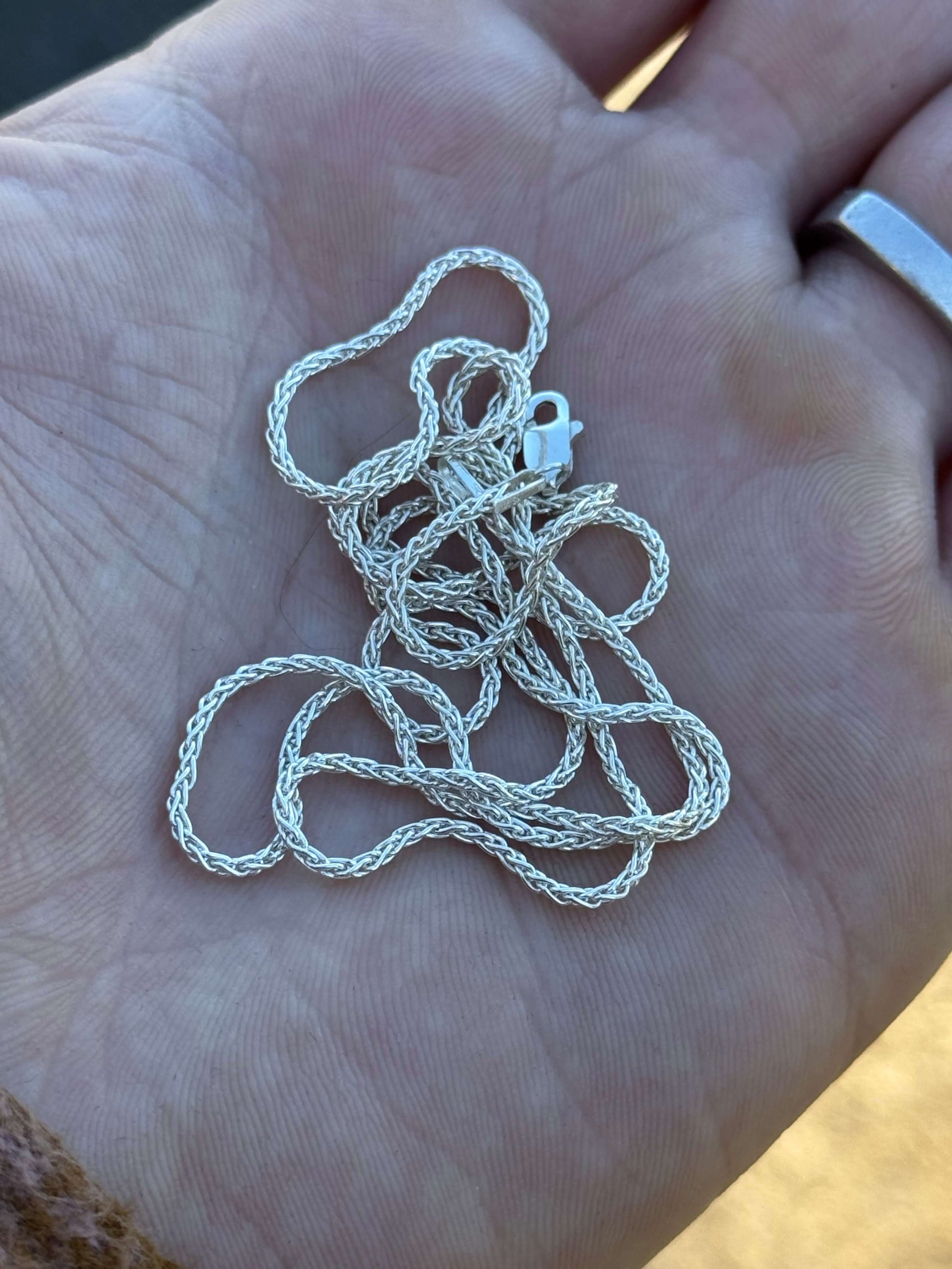 Hand holding a polished coiled silver chain 