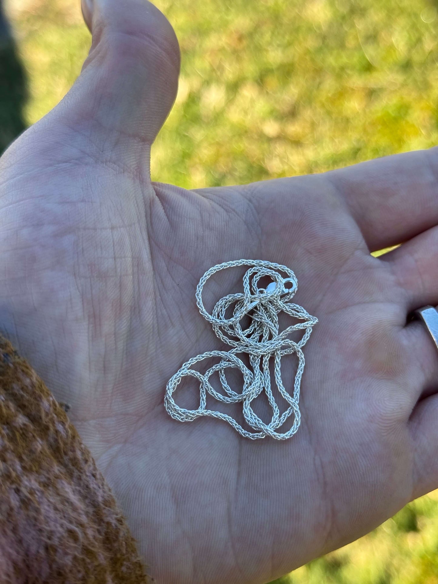 Hand holding a polished coiled silver chain 