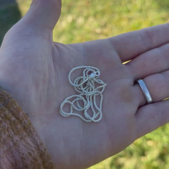 Hand holding a polished coiled silver chain 