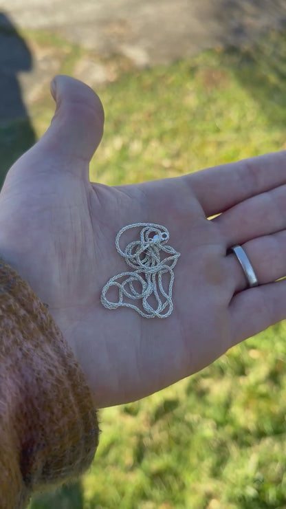 Hand holding a polished coiled silver chain 